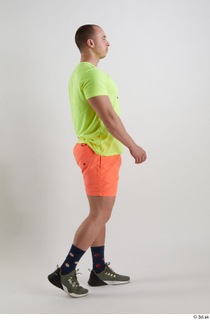 Joel  1 dressed green sneakers orange shorts side view…